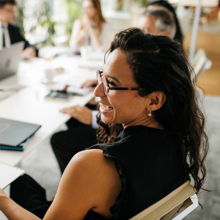Would a Mastermind Group benefit my business? Lady smiling at a colleague around a meeting table.